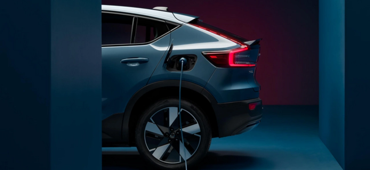 Vue latérale d’un Volvo C40 bleu en charge dans un cadre moderne et minimaliste