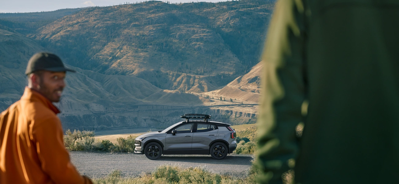Deux personnes près d’un Volvo EX30 Cross Country avec des montagnes en arrière-plan