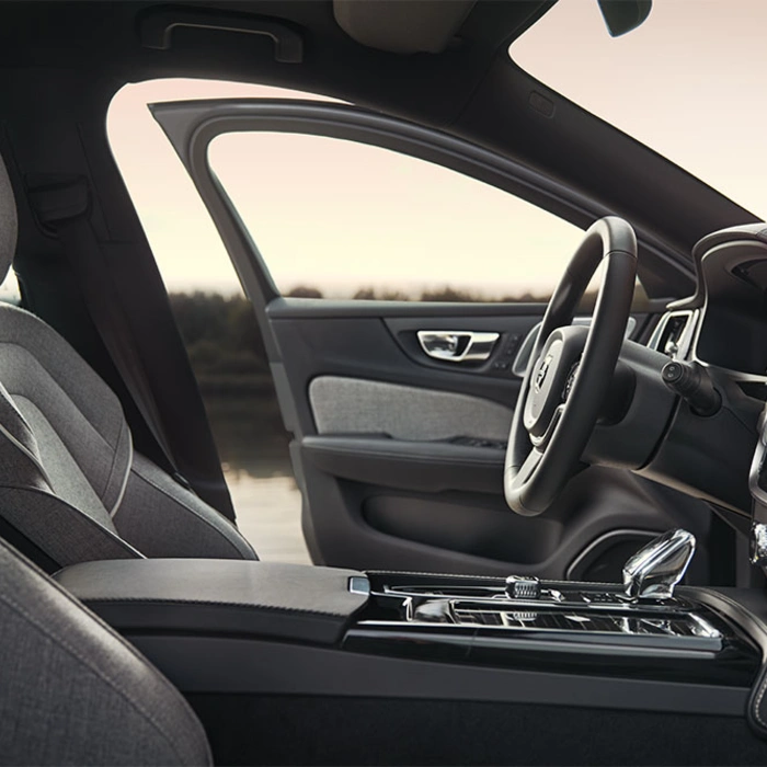Intérieur d’un Volvo V60 avec porte conducteur ouverte, volant, tableau de bord et sièges avant visibles