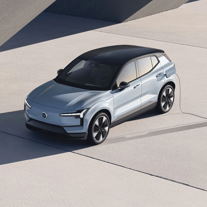 Volvo EX30 argenté en charge dans un décor moderne avec ombres géométriques