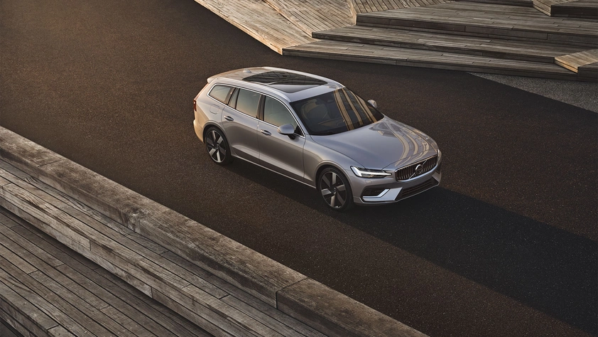 Volvo V60 argenté garé sur surface bois et asphalte, avec structures géométriques en bois en arrière-plan