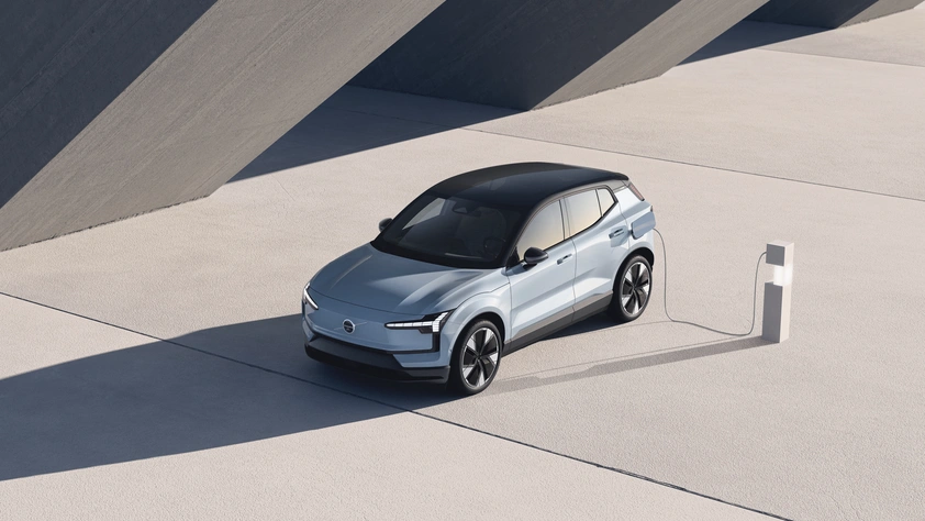 Volvo EX30 argenté en charge dans un décor moderne avec ombres géométriques