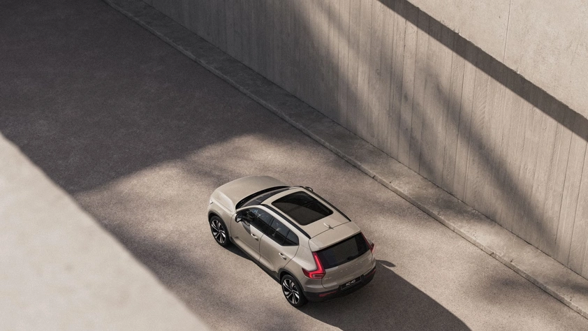 Vue aérienne d’un Volvo XC40 beige avec toit ouvrant roulant en zone urbaine entre murs en béton et ombres
