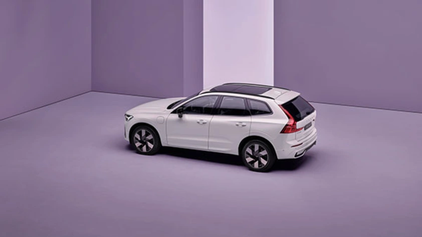 SUV blanc garé dans une pièce violette minimaliste avec une bande verticale blanche sur le mur.
