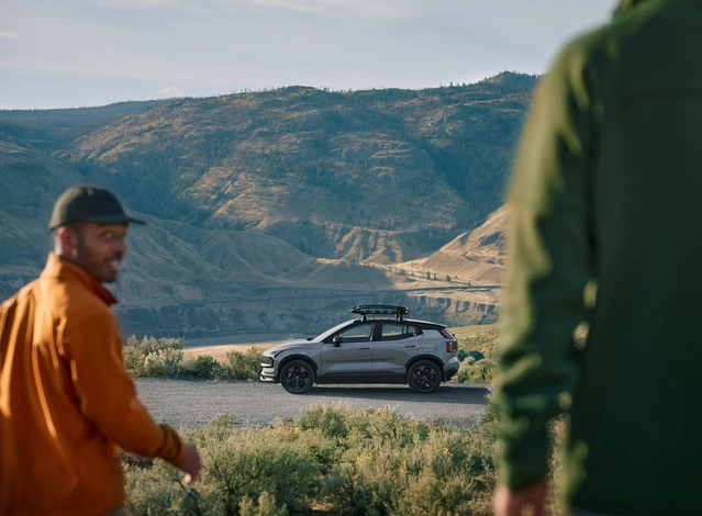 Deux personnes près d’un Volvo EX30 Cross Country avec des montagnes en arrière-plan
